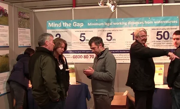 The Farming & Water Scotland show stand with people mingling and talking on an internal show stand with the Farming & Water Scotland 'Know The Rules' information banner in the background.